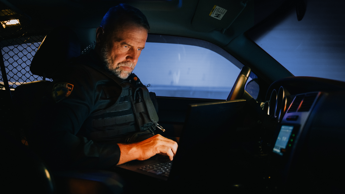 iStock-1480307992_blue Police officer examining a laptop screen